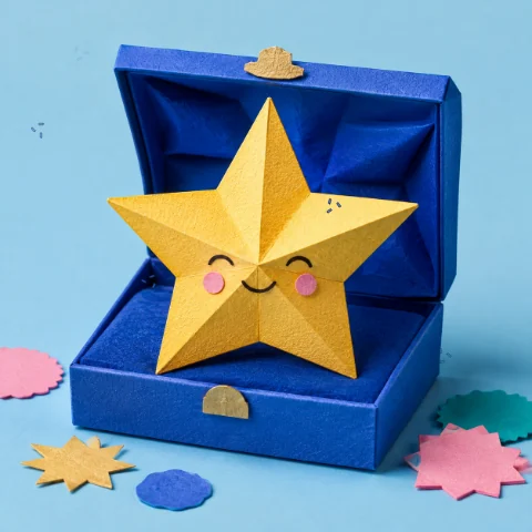 A smiling gold paper star in an open blue box, with animated paper confetti.